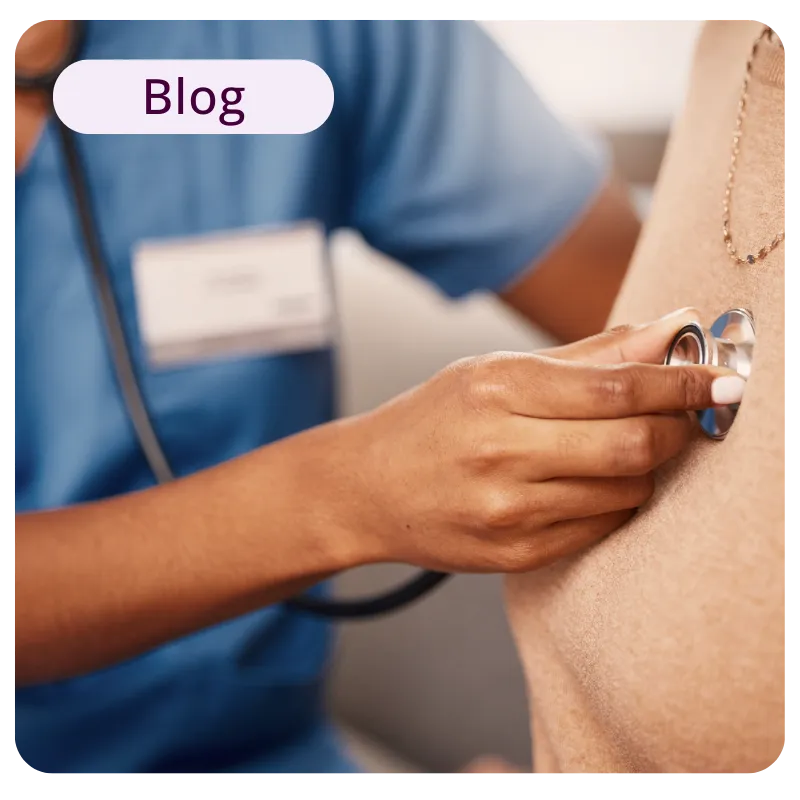 Healthcare professional in blue scrubs using a stethoscope to examine a patient's heart